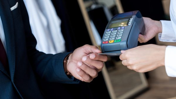 cropped shot of businessman paying by credit card and terminal in boutique